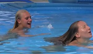 Two beautiful girls swimming and licking by the pool
